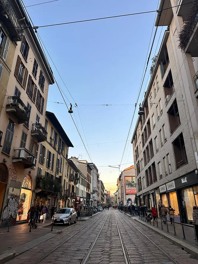 City street with buildings, people, and a clear blue sky.